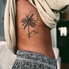 a woman's stomach with a palm tree tattoo on her left side ribcage