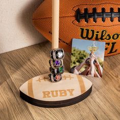 an image of a football and ring holder on a wooden table next to a photo