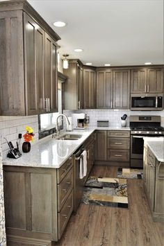 a kitchen with wooden cabinets and white marble counter tops is shown in this image, there are two rugs on the floor