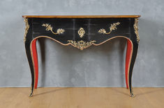 an antique black and red console table with gold accents