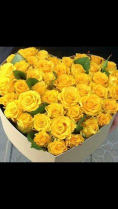 a heart shaped box filled with yellow roses