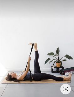 a woman doing yoga on a mat in front of a plant and potted plant