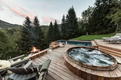 a hot tub sitting on top of a wooden deck next to a fire pit in the middle of a forest