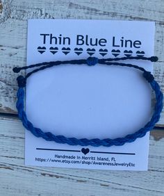 the thin blue line bracelet is shown on top of a white card with black string