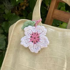 a crocheted flower is attached to a purse with a pink and green handle