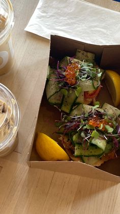 an open box with some food inside of it on a table next to a drink