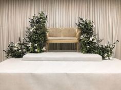 a chair sitting on top of a white table covered in flowers and greenery next to a bench