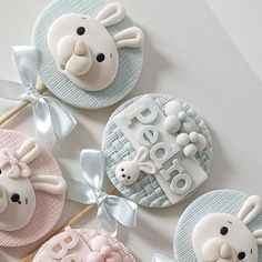 three decorated cookies are sitting on top of a white table with silver ribbons and bows