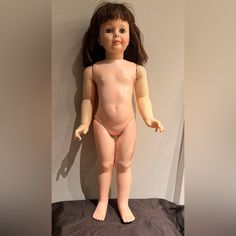 a naked doll standing on top of a bed