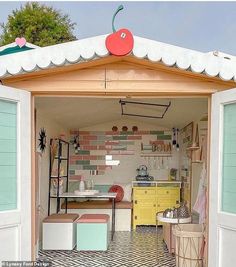 an open garage with lots of furniture and decor on the outside, in front of a tree