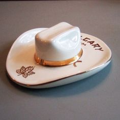 a small white hat sitting on top of a saucer with the word eat pray written on it