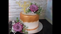 there is a wedding cake with purple flowers on the top and gold trimmings