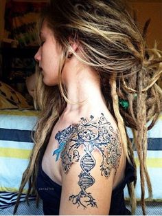 a woman with long dread locks and tattoos on her back is looking at the camera