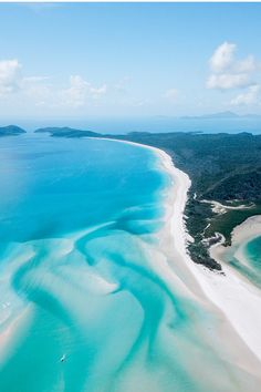 an aerial view of the ocean and beach from above, with white sand in the foreground