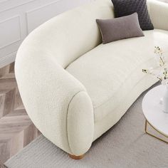 a white couch sitting on top of a wooden floor next to a vase filled with flowers