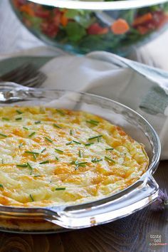 a casserole dish with cheese and herbs in the center on a wooden table