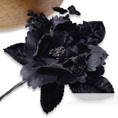 a black flower is sitting on top of a piece of wood and some other things