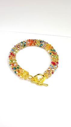 a bracelet with multicolored beads and a gold hook on it's end