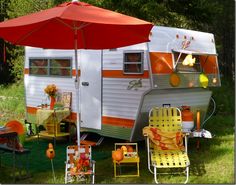 an orange and white camper parked in the grass