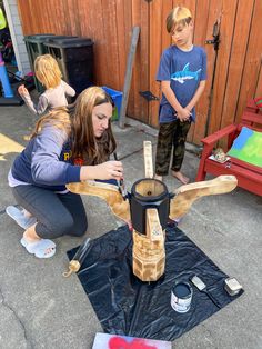 two children and an adult are working on a sculpture