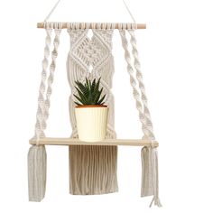 a white macrame hanging shelf with a potted plant on it