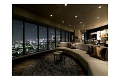 a living room filled with lots of furniture and windows overlooking the city lights at night