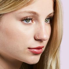 a woman with long blonde hair and blue eyes is looking at the camera while wearing an earring