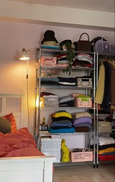 a bedroom with a bed, closet and shelves filled with clothes on top of them