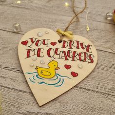 a wooden heart shaped ornament with a rubber ducky on the front saying, you drive the ducks