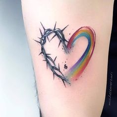 a colorful heart with a crown of thorns tattoo on the side of a woman's thigh