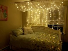 a bed sitting under a window covered in lights