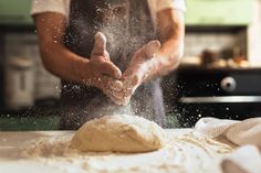 a person making bread on top of a table with flour sprinkled around it