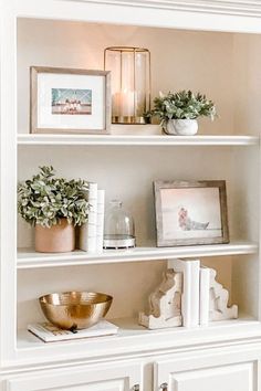 a white book shelf filled with books and plants