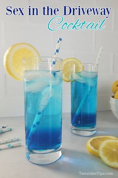 two glasses filled with blue liquid next to lemons