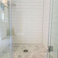 a bathroom with white tile and hexagonal floor tiles on the shower stall door