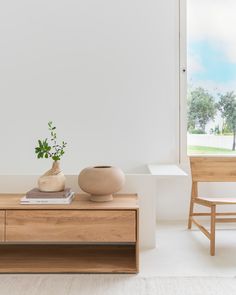 a wooden table with a vase on it next to a chair