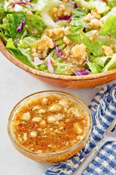 a bowl of salad with dressing next to it on a blue and white cloth,