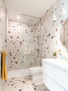 a bathroom with a toilet, sink and shower in it's own area that is decorated with multicolored tiles