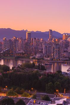 the city skyline is lit up at night with mountains in the backgrouund