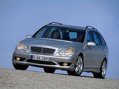 a silver car driving down a road next to the ocean