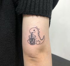 a small tattoo on the arm of a woman with a dinosaur holding a glass of wine