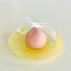 an egg on a yellow plate with a white ribbon