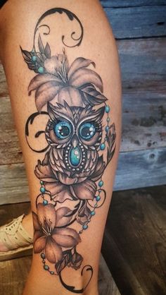 an owl with blue eyes and flowers on its leg is shown in this tattoo design