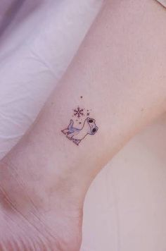 a small tattoo on the ankle of a woman's left foot, with a dog and snowflakes