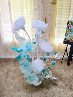 a vase filled with blue and white flowers on top of a carpeted floor next to a window