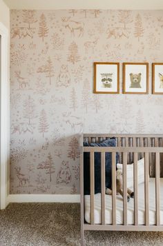 a baby's crib in the corner of a room with two pictures on the wall