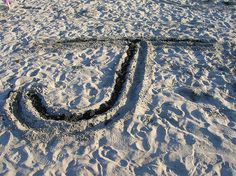 there is a sign made out of sand that looks like the letter j on the beach