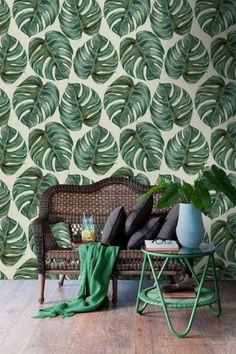 a living room with a wicker couch and wallpaper that has green leaves on it