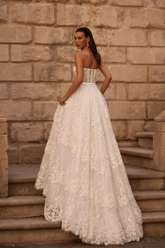 a woman in a white wedding dress standing on steps with her back to the camera