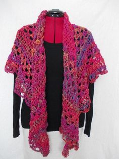 a crocheted shawl is displayed on a mannequin